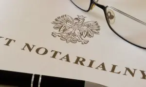 Okulary i długopis leżą na dokumencie z godłem Polski i napisem "AKT NOTARIALNY". To dokument, który wymaga opłaty, czyli taksa notarialna.