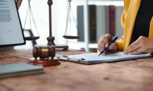 Prawnik analizuje dokumenty, by ustalić, jak liczyć koszty uzyskania przychodu. W tle waga sprawiedliwości i młotek sędziowski.