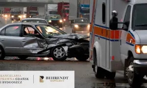 Wypadek w drodze do pracy. Zmiażdżony srebrny samochód i karetka na mokrej drodze.