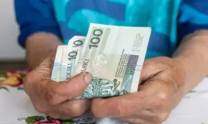 Dłonie trzymają polskie banknoty. Zastanawiasz się, ile wynosi umowa zlecenie na godzinę netto?