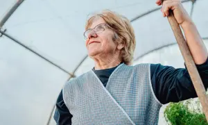 Starsza kobieta w fartuchu, z łopatą w dłoni, wygląda z nadzieją. Może to symbol jej przyszłości, wspieranej przez rodzicielskie świadczenie uzupełniające.