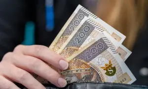 Dłoń trzyma banknoty 200 zł. Kto nie ma prawa do zasiłku dla bezrobotnych, musi radzić sobie sam.