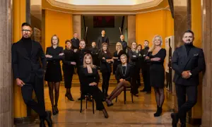 Grupa profesjonalistów w eleganckich strojach pozuje w holu.