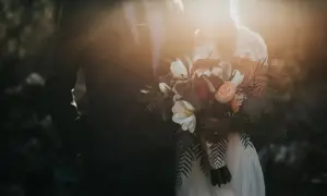 Para młoda w blasku słońca, trzymająca bukiet. To idealny moment na urlop okolicznościowy.