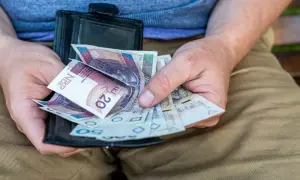Dłonie trzymają portfel z polskimi banknotami. To może być świadczenie przedemerytalne, które zapewnia stabilność finansową.