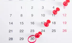 Kalendarz z pinezkami zaznaczającymi dni. Zastanawiasz się, ile godzin pracy w miesiącu?
