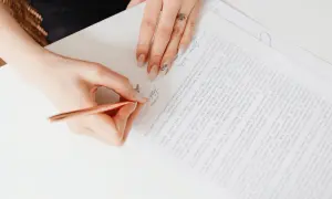 Dłoń pisze na dokumencie, podpisując umowę cfr-1.