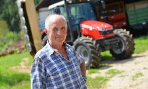 Rolnik w kratę, z dumą prezentuje swój nowy traktor. To dla niego ważny dzień, bo właśnie otrzymał fakturę RR za zakup.
