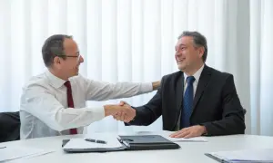 Dwóch mężczyzn w garniturach ściska sobie dłonie, symbolizując pomyślne zakończenie negocjacji i podpisanie umowy kredytowej.