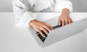 Dłonie piszą na laptopie, szukając informacji o zaświadczenie o niezaleganiu ZUS.