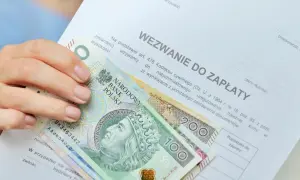 Dłoń trzyma banknoty 100 i 200 zł na wezwaniu do zapłaty. Zastanawiasz się, ile zarabia komornik?