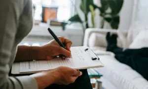 Psycholog notuje na kartce. Zastanawia się, ile zarabia psycholog, analizując swoje wydatki i dochody.
