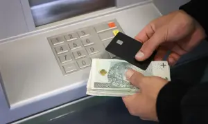 Ręce trzymające kartę i banknoty przy bankomacie. Dowiedz się, jak wpłacić pieniądze na konto.