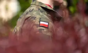 Żołnierz w mundurze moro z polską flagą na ramieniu, symbol służby i przyszłej emerytury wojskowej.
