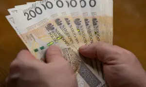 Dwie ręce trzymają plik banknotów po 200 zł. To może być wypłata 5000 brutto.