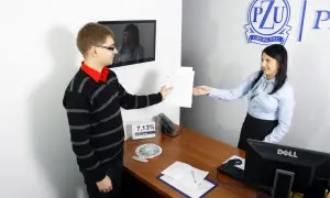 Mężczyzna podaje dokumenty kobiecie przy biurku w biurze PZU.