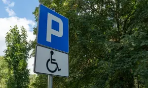 Znak parkingowy z symbolem osoby na wózku inwalidzkim, wskazujący miejsca dla osób z różnymi stopniami niepełnosprawności.