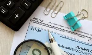 Rozliczenie dochodów z zagranicy przykład: PIT-38, kalkulator, lupa i pieniądze.