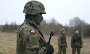 Żołnierz w kamuflażu, z polską flagą na ramieniu, trzyma broń. Zastanawiasz się, ile zarabia żołnierz netto?