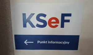 Tablica informacyjna KSeF. Strzałka w lewo wskazuje punkt informacyjny, gdzie można uzyskać pomoc podczas szkolenia.