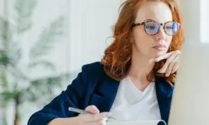 Kobieta w okularach z modną oprawką, pracująca przy laptopie. Dofinansowanie do okularów może pomóc w zakupie takich stylowych oprawek.