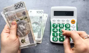 Ręka trzyma banknoty 200 zł i 100 zł, obok kalkulator z wyświetloną kwotą 50000. Czy to prognoza wynagrodzenia minimalnego 2026?