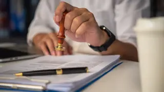 Dłoń z pieczęcią nad dokumentem. Czy umowa zlecenie chroni przed komornikiem?