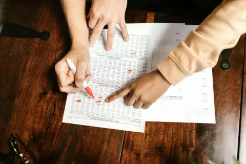 Ręce przeglądają tabelę z danymi finansowymi. Określenie, od jakiej kwoty coś jest traktowane jako środek trwały, wymaga analizy tych liczb.