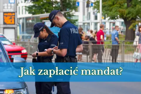 Dwóch policjantów w mundurach dyskutuje, jak zapłacić mandat przelewem. W tle ludzie i budynki.