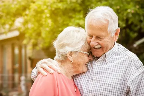 Szczęśliwi seniorzy w małżeństwie, uśmiechnięci, czule objęci. Ich miłość kwitnie, jakby otrzymali dodatkowe wsparcie, niczym 500 plus dla seniora w małżeństwie.