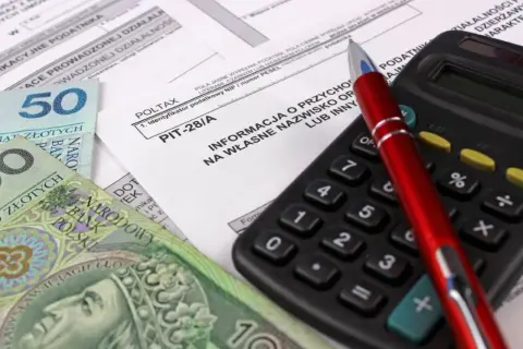 Formularz PIT-28/A, polskie banknoty i kalkulator. Przygotowanie do rozliczenia najmu.