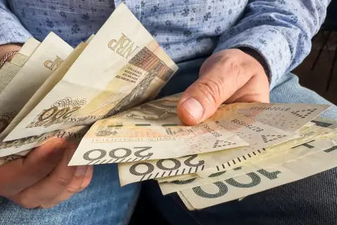 Ręce trzymające polskie banknoty 100 i 200 zł. Czy 800 plus wlicza się do dochodu?