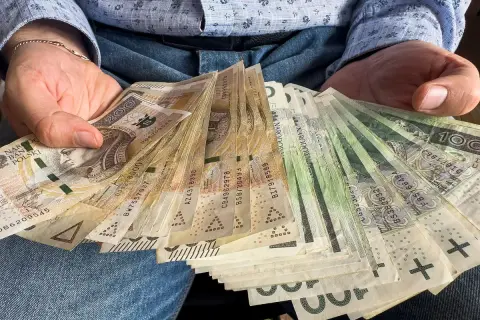 Ręce trzymające stos banknotów 100 i 200 zł. To darowizna od rodziców na nowy cel.