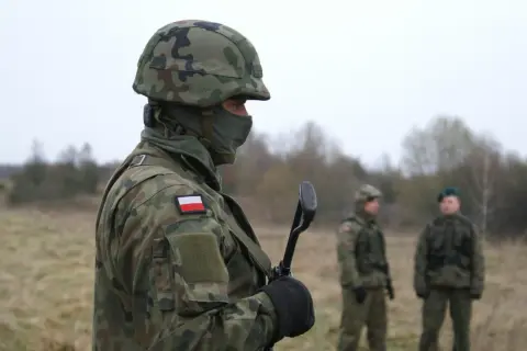 Żołnierz w kamuflażu, z polską flagą na ramieniu, trzyma broń. Zastanawiasz się, ile zarabia żołnierz netto?
