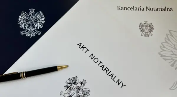 Elegancki długopis leży obok dokumentu z napisem "AKT NOTARIALNY" i godłem Polski.