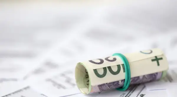 Zrolowane banknoty na dokumentach podatkowych. Przygotowanie do rozliczenia ulgi rehabilitacyjnej 2026.