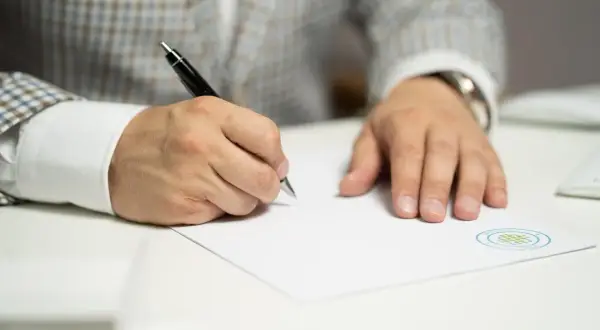Mężczyzna w eleganckim garniturze podpisuje dokument. To ważny wniosek o stwierdzenie nabycia spadku, który wymaga precyzji i uwagi.