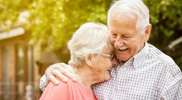 Szczęśliwi seniorzy w małżeństwie, uśmiechnięci, czule objęci. Ich miłość kwitnie, jakby otrzymali dodatkowe wsparcie, niczym 500 plus dla seniora w małżeństwie.