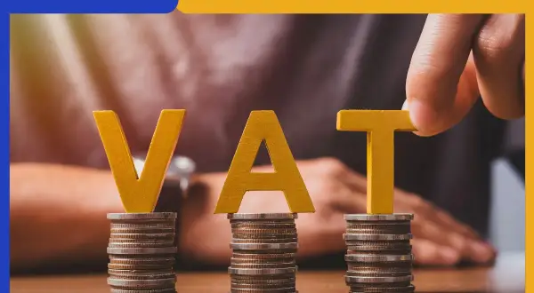 Litery "VAT" na stosach monet. Dłoń układa literę "T". Temat: metoda kasowa w pytaniach i odpowiedziach.
