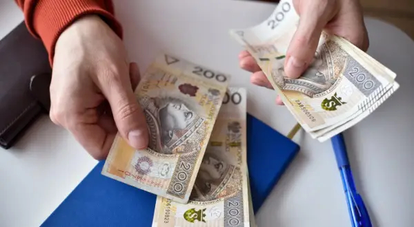 Ręce liczą banknoty 200 zł. Może to być wypłata, oszczędności, albo nawet renta alkoholowa, którą ktoś chce przeznaczyć na coś innego.