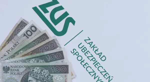 Pieniądze, w tym banknoty 100 i 200 zł, leżą obok logo ZUS. To ważny dodatek dopełniający, symbolizujący świadczenia i składki.