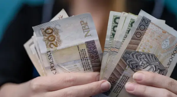 Dłonie trzymające plik banknotów 200 zł. Czy to najwyższa emerytura w Polsce?