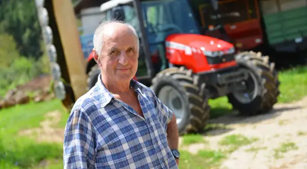 Rolnik w kratę, z dumą prezentuje swój nowy traktor. To dla niego ważny dzień, bo właśnie otrzymał fakturę RR za zakup.
