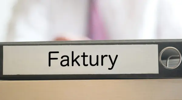 Segregator z napisem "Faktury" na biurku, gotowy do uporządkowania dokumentacji.