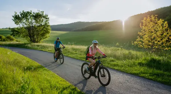 Dwie osoby na rowerach elektrycznych cieszą się malowniczą trasą. Dofinansowanie do roweru elektrycznego ułatwia takie wycieczki.