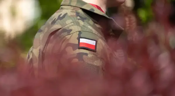 Żołnierz w mundurze moro z polską flagą na ramieniu, symbol służby i przyszłej emerytury wojskowej.