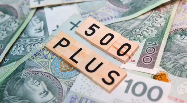 Litery "500 PLUS" na tle polskich banknotów. Symbol wsparcia finansowego, np. 500 plus dla niepełnosprawnych.