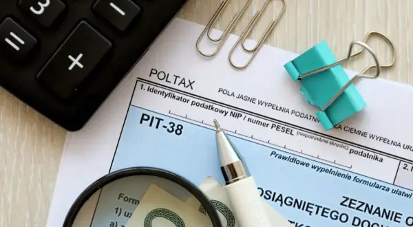 Rozliczenie dochodów z zagranicy przykład: PIT-38, kalkulator, lupa i pieniądze.