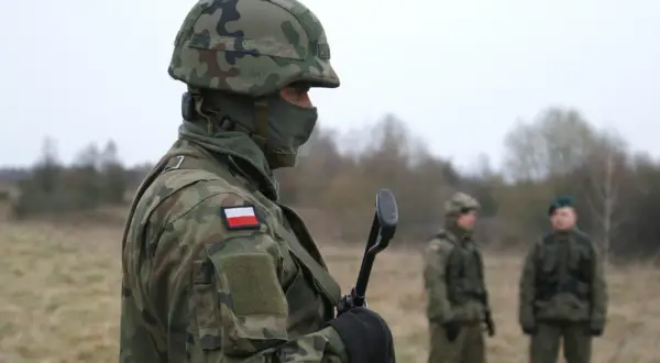 Żołnierz w kamuflażu, z polską flagą na ramieniu, trzyma broń. Zastanawiasz się, ile zarabia żołnierz netto?