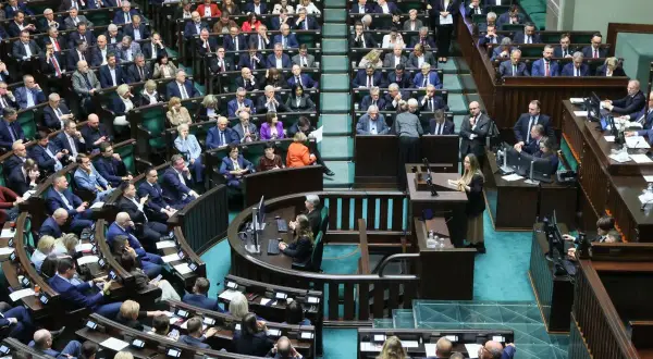 Posłowie w sali sejmowej, dyskutują o tym, ile wynosi dieta poselska.
